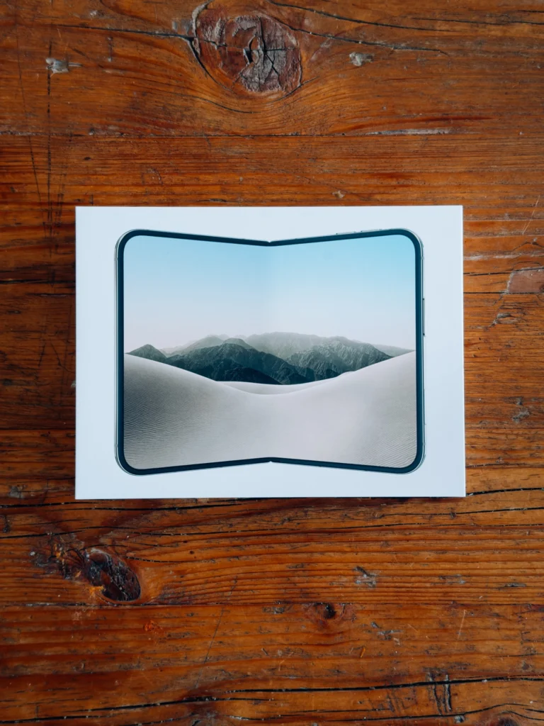 Weiße iPhone-Duo-Box von oben auf einem Holztisch, auf dem Deckel das aufgeklappte Duo