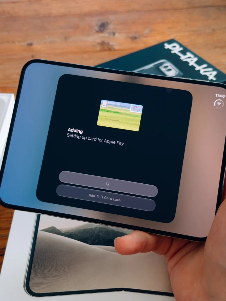 Aufgeklapptes iPhone Duo in der Hand beim Einrichten einer Karte für Apple Pay